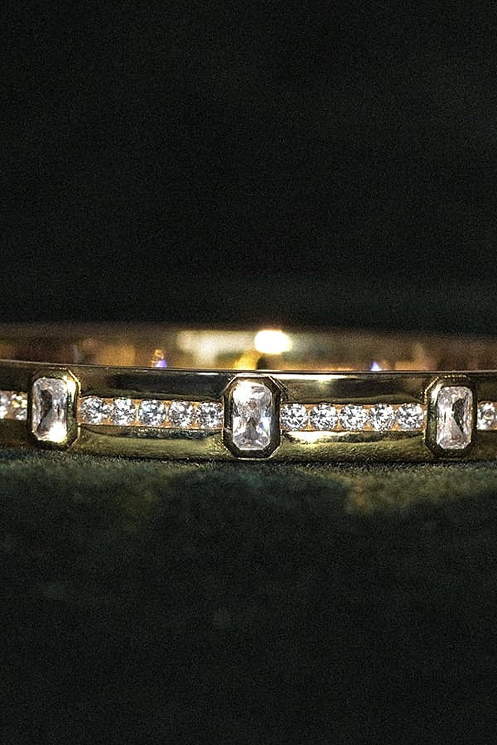 Guld armbånd med sten på grøn fløjl